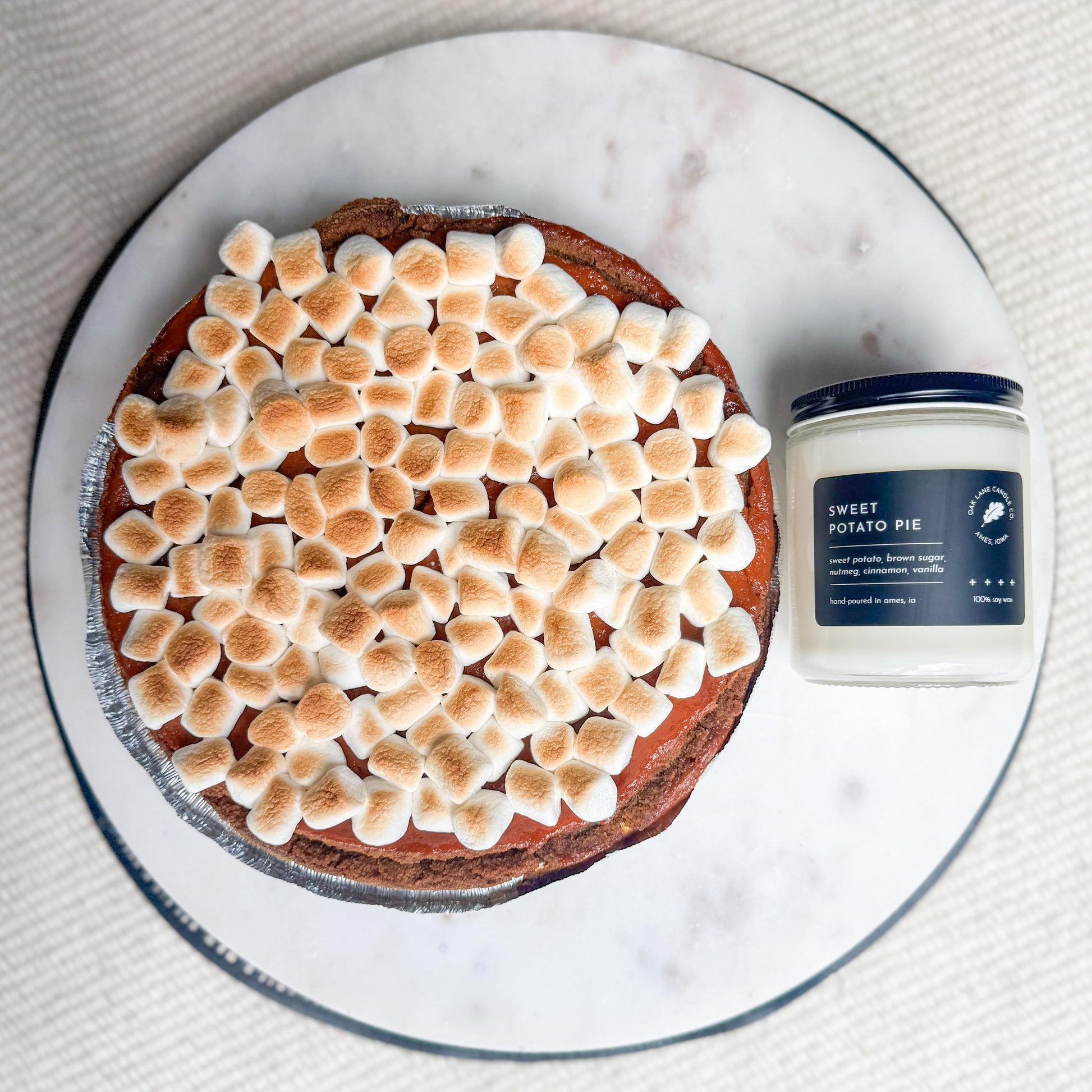 Sweet potato pie with toasted marshmallows on a plate next to a jar labeled 'Sweet Potato Pie'.